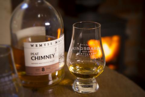 Bottle of whisky with glass by log fire