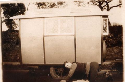 Old sepia photo of a mechanic fixing a flat tyre
