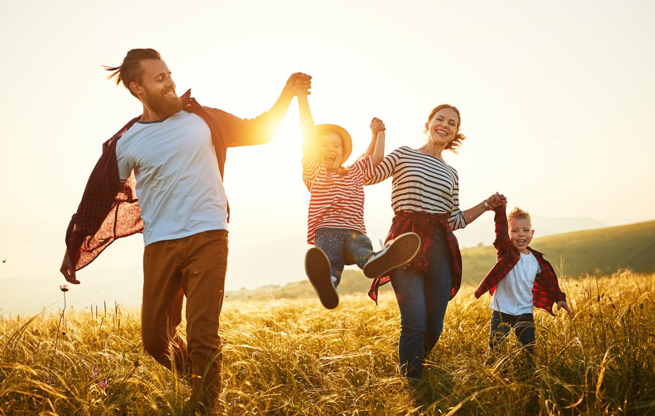 Active family walking through a corn field as the sun sets