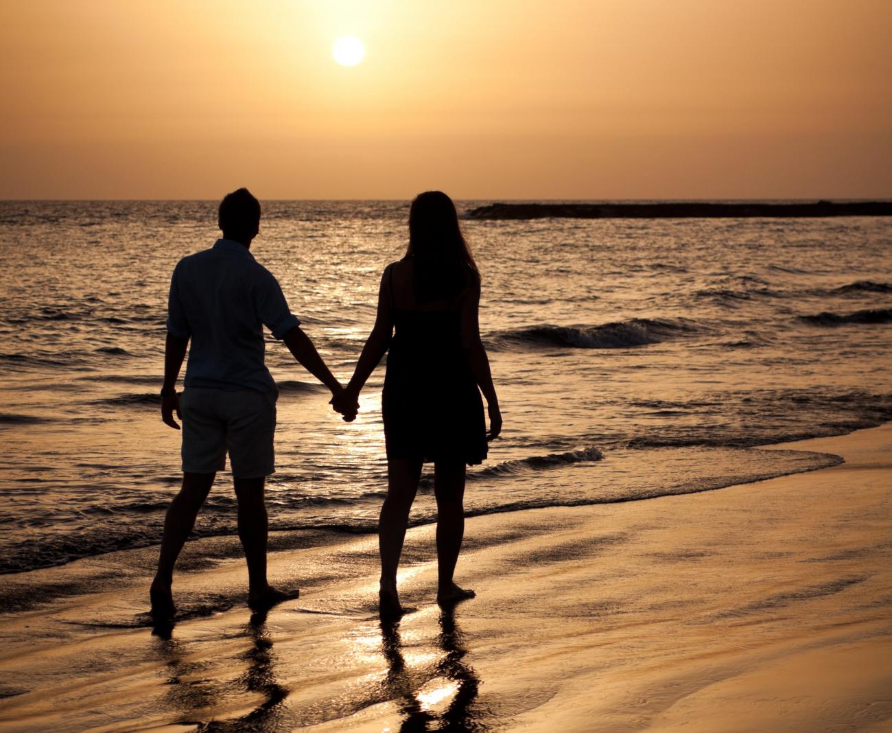 Couple walking on beach at sunset