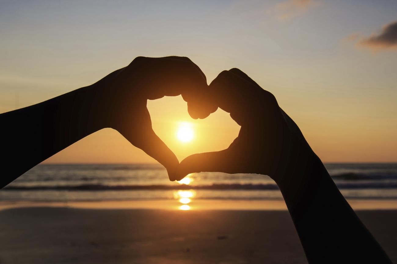 Heart shape hand at sunset