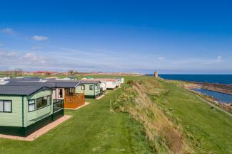 holiday homes on grass with sea in the distance