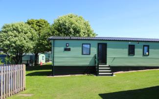 Signature Value holiday home exterior on grass with blue sky