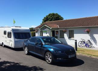 Car towing caravan arrives at St Andrews Holiday Park on a sunny day