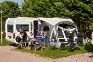 Adults having a bbq outside their caravan on Clifftops Touring Field at St Andrews Holiday Park