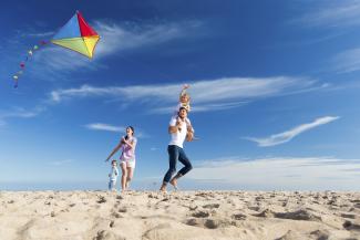Family flying kite on a sunny beach