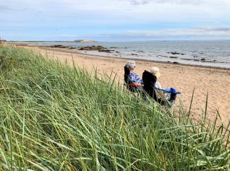 Ladies sitting in the sunshine on the beach at Largo Bay